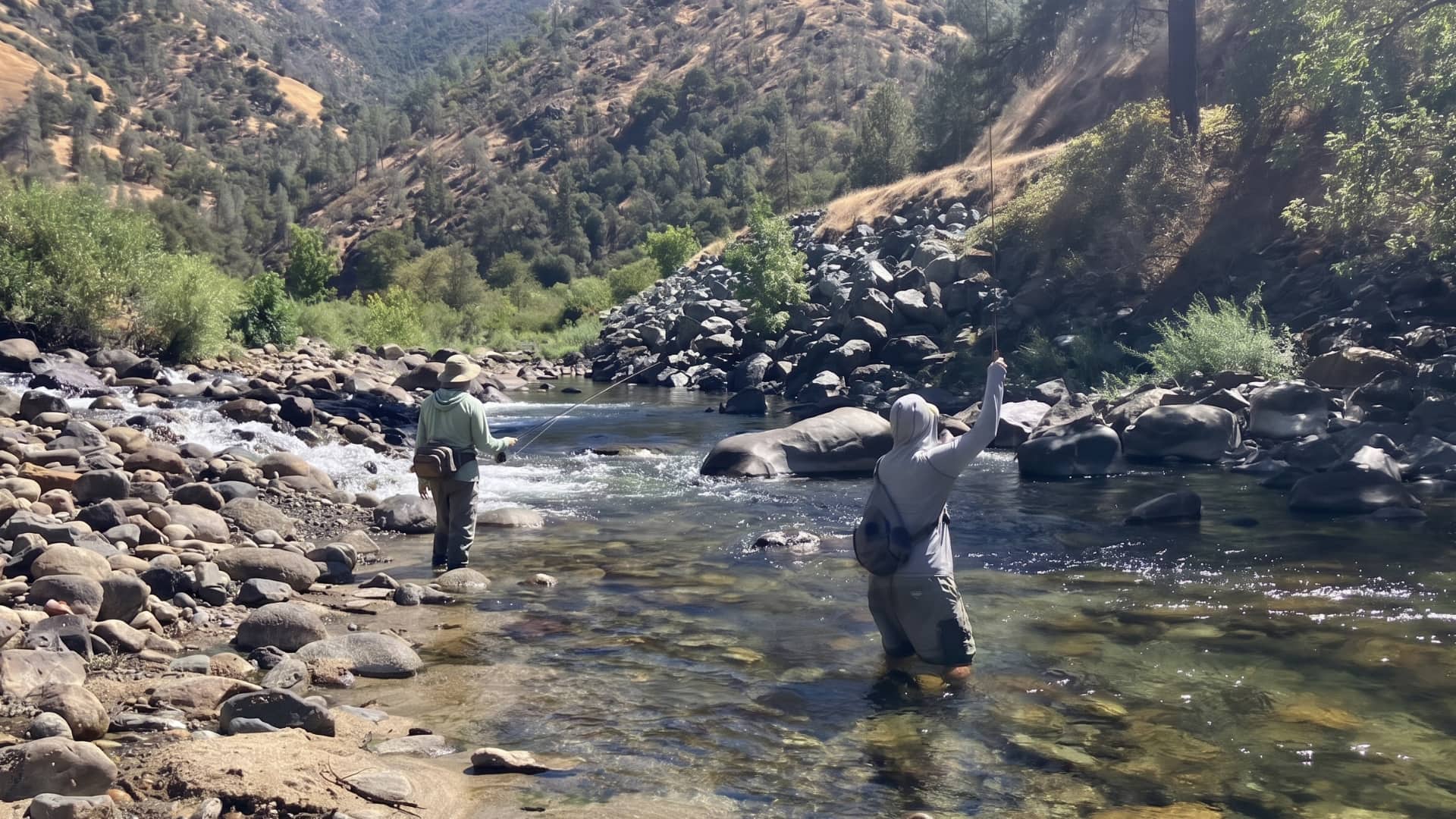 Two anglers fly fishing a scenic High Sierra river canyon
