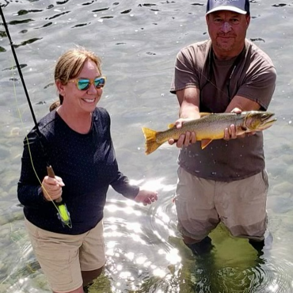 Fly fishing guide and client holding a wild trout in a High Sierra river